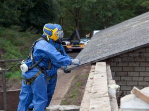 operatori controllano una lastra di amianto del tetto di una casa