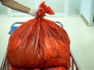 operatore sanitario tiene busta di rifiuti ospedalieri